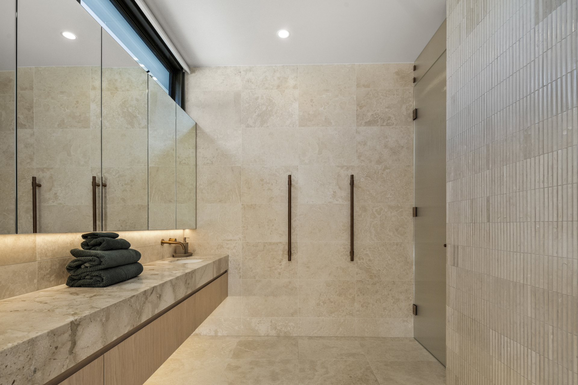 Textured stone shower and softly lit vanity