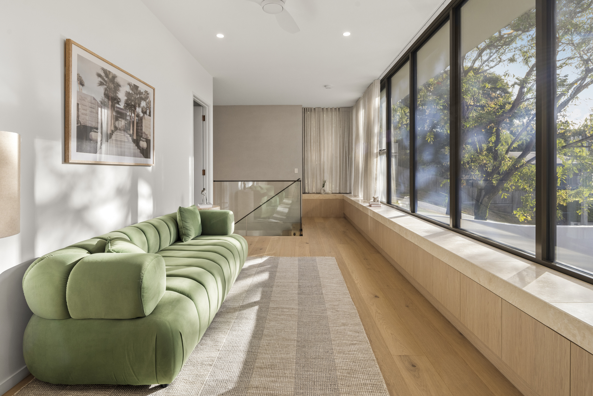 Upper lounge framed by glass and subtropical greenery