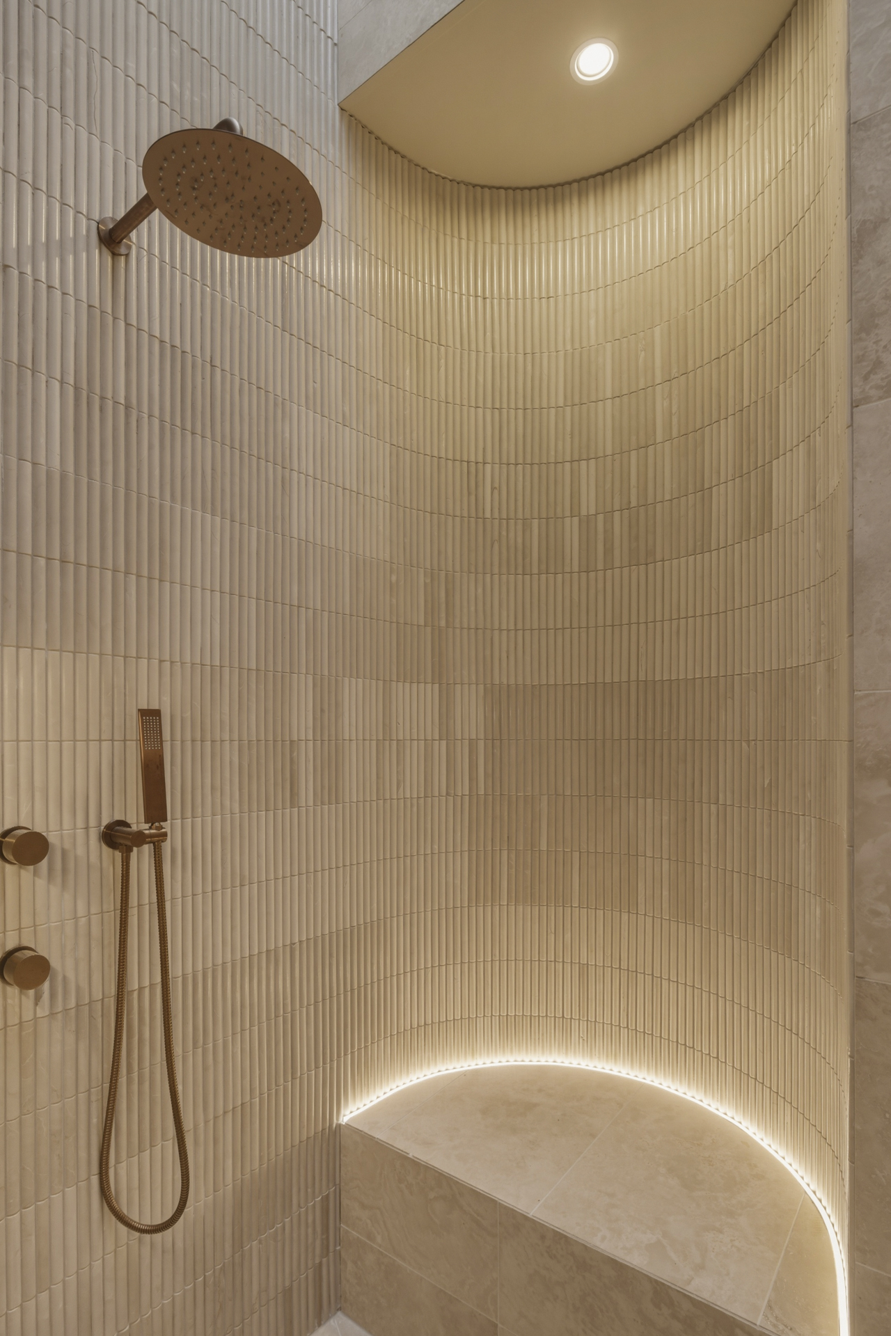 Curved stone shower with bronze detailing