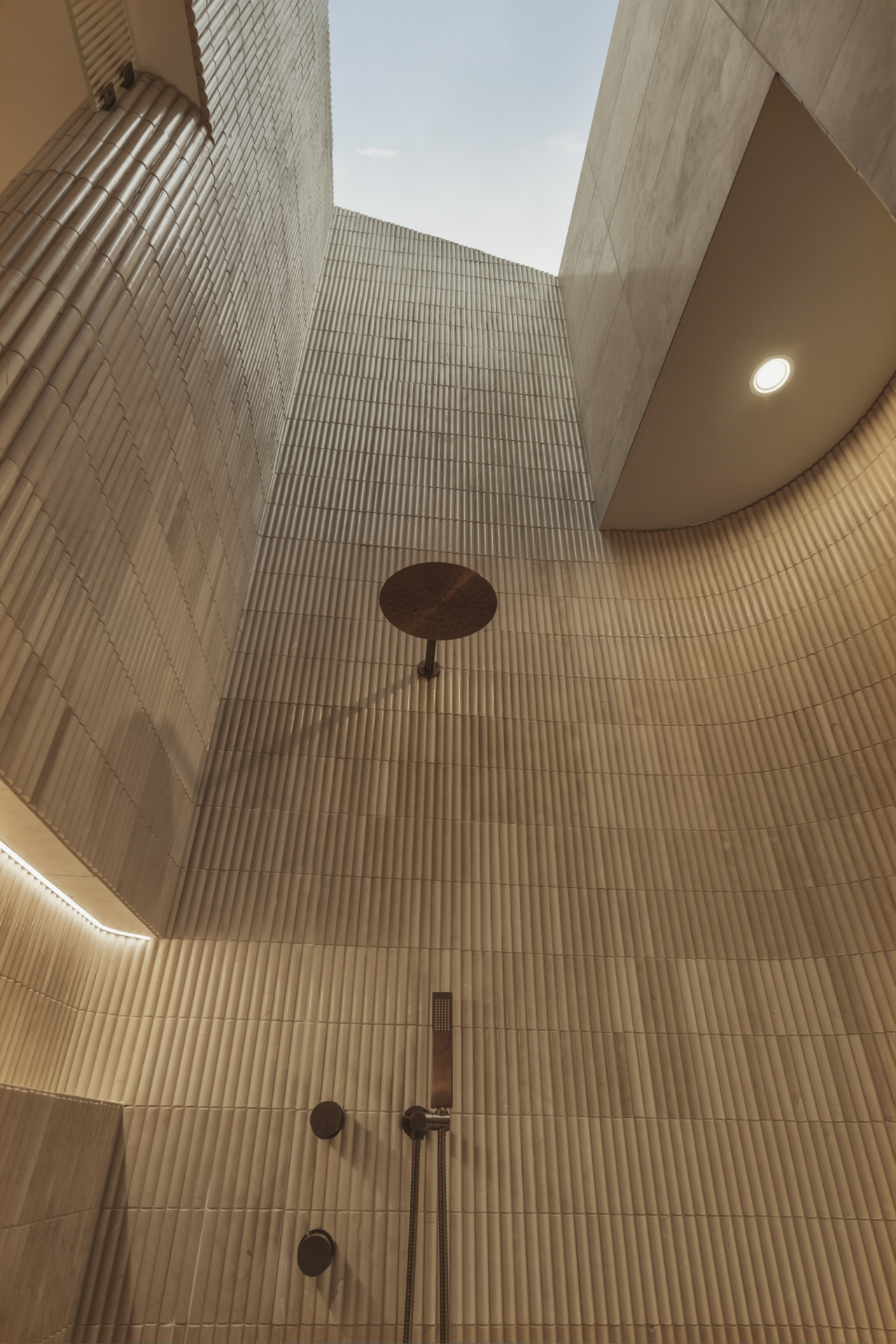 Sculptural skylight above the curved stone bathroom